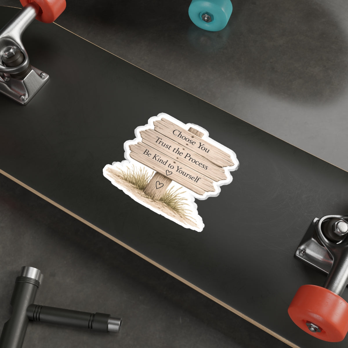 Close view of the wooden beach sign quote sticker on a black skateboard